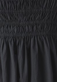 Tissu de robe noire avec des détails de smocks froncés, créant une apparence texturée avec des plis doux tout au long.