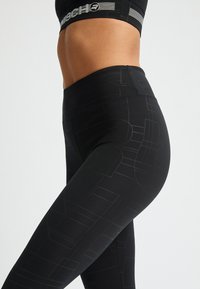 Leggings neri con un motivo geometrico in una tonalità di nero più scura, con vita alta e tessuto liscio ed elastico.