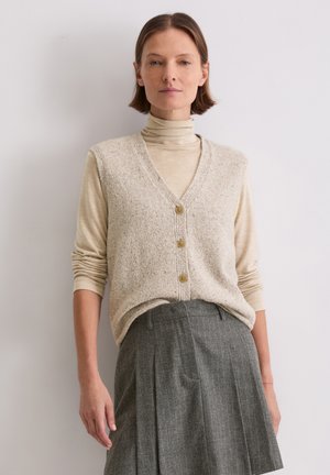 Light beige knitted vest with a V-neck and three buttons, layered over a beige turtleneck. Gray pleated skirt with subtle pinstripes.