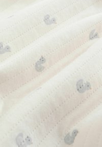 Pehme valge kangas õrna õmmeldud triipude ja väikeste hallide pardipoegade trükkidega, mis on ühtlaselt üle kogu pinna jaotatud.