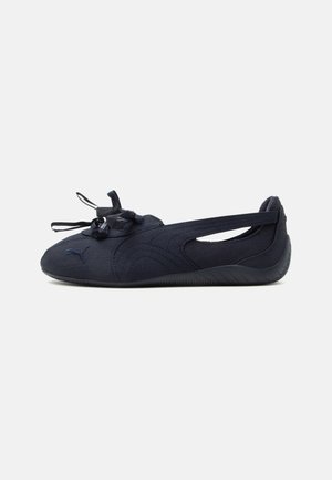 Must minimalistlik Puma lameda jalanõu, mis on ees paeltega ja külgmise lõikega, kujundatud kergeks mugavuseks ja paindlikkuseks.