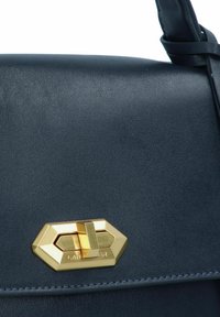Borsa a mano in pelle blu navy con superficie testurizzata, dotata di una chiusura geometrica in oro e dettagli di cucitura a contrasto.