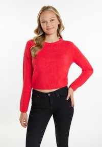 Rode cropped trui met lange mouwen van een zachte, fuzzy stof. Gepaard met strakke zwarte jeans met een knoopsluiting.