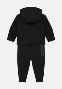 Set di felpa e pantaloni della tuta Nike neri, realizzato in tessuto morbido, con cappuccio, tasca con zip e polsini a coste per una vestibilità aderente.