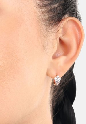 Pendientes de aro en oro rosa con diseño floral, que presentan cinco piedras de strass transparentes dispuestas en un racimo para añadir brillo y detalle.