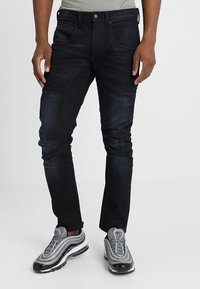 Mörk tvättade jeans med slim fit, som har fem fickor, knap stängning och subtil blekning vid lår- och knäområdena.