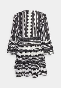 Robe noire et blanche avec un motif géométrique, manches longues avec volants, taille froncée et jupe à niveaux. Texture lisse.