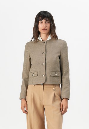 Veste cropped à carreaux marron avec un col rond, des boutons métalliques et deux poches avant, accompagnée de pantalons taille haute beige.