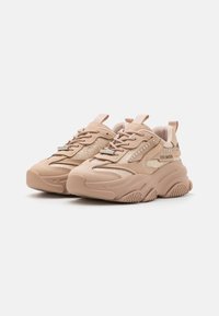 Baskets de sport beige avec des panneaux en maille, des accents texturés, une semelle en caoutchouc et des strass décoratifs ; comprennent des lacets et des poignées.