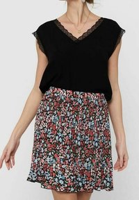 Černý top s výstřihem do V a krajkovým lemem, doplněný květinovou sukní s červenými, růžovými a modrými vzory na černém pozadí, pružným pásem.