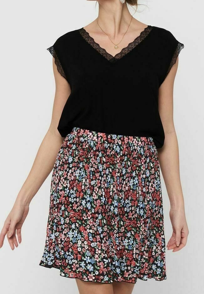 Černý top s výstřihem do V a krajkovým lemem, doplněný květinovou sukní s červenými, růžovými a modrými vzory na černém pozadí, pružným pásem.