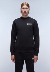 Zwarte sweatshirt met ronde hals, lange mouwen en geribde manchetten. Heeft een logo patch op de borst. Vlotte textuur, casual pasvorm.
