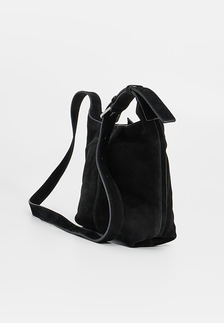 Bolso de ante negro con forma estructurada, que cuenta con una correa ancha y cierre en la parte superior. Los acentos incluyen una textura suave y un ribete en contraste.