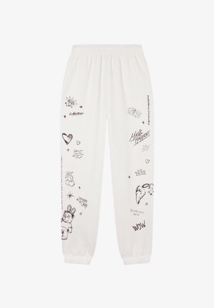 Białe dresy z czarnymi bazgrołami i odręcznie napisanymi frazami takimi jak "Magia się zdarza", serca, kostki do gry, wiśnie, skrzydła i pluszowy miś w króliczym kostiumie.