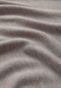 Lysegråt stof med blød struktur, der har blide bølger og et fint vævemønster, hvilket skaber et glat og flydende udseende.