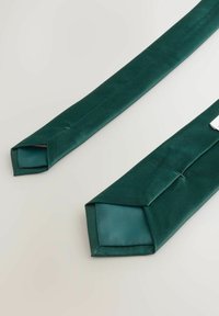 Zelená saténová látka zviazaná hladkým, uhlovým dizajnom. Konce sú zúžené, ukazujúc lesknúcu sa povrchovú úpravu a kontrastnú vnútornú textúru.