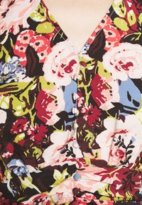 Gros plan d'une robe fleurie avec un profond décolleté en V et de petits boutons recouverts de tissu sur le devant en rouge, rose, vert, bleu et noir.