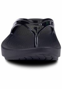 Mustat flip-flop-sandaalit kiiltävällä materiaalilla, tasapohja ja teksturoitu pohja. Sandaaleissa on thong-nauhamalli ja korotettu kanta.