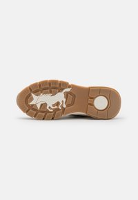 Suela de goma marrón con una superficie texturizada, que presenta la silueta de un animal corriendo en blanco y un gráfico de estrella. Patrón de agarre fuerte para tracción.