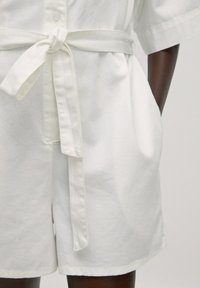 Witte katoenen short-sleeve jumpsuit met een gestrikt tailleband, zijzakken en een knoopsluiting aan de voorkant met een ontspannen pasvorm.