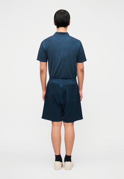 Μπλε κοντομάνικη πόλο μπλούζα σε ναυτικό μπλε, σετ με ταιριαστά μπλε σορτς. Το ύφασμα έχει διακριτή υφή, με ελαστική μέση και πίσω τσέπη.