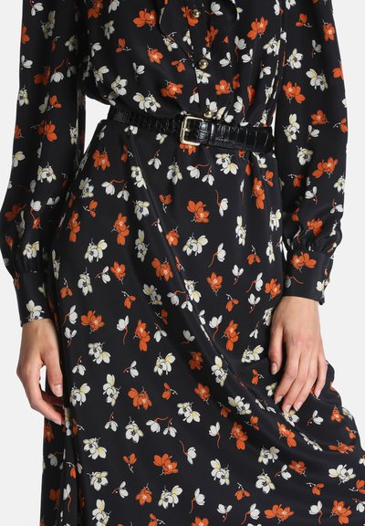 Robe noire avec imprimé floral orange et blanc, manches longues, boutons dorés et ceinture noire texturée avec boucle carrée dorée.