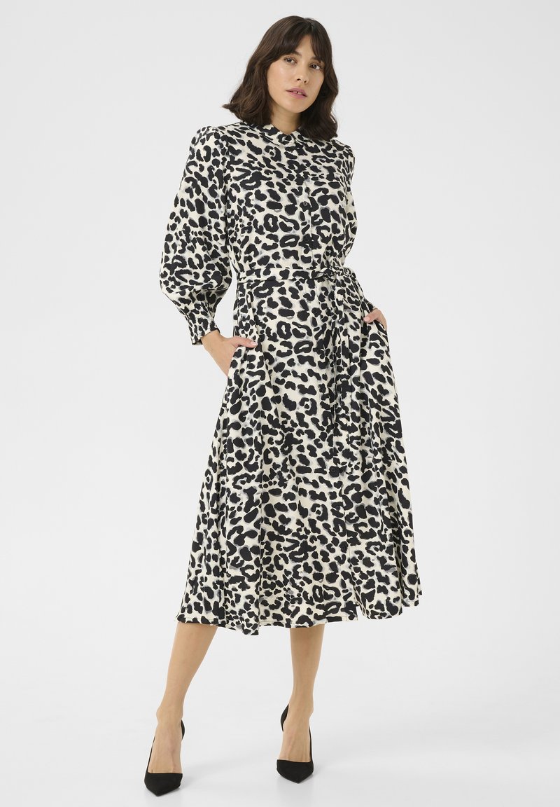 Midi-jurk met luipaardprint, een aansluitende taille, lange mouwen en zakken. De stof is glad met zwart en beige kleuren. Zwarte hakken maken de look compleet.
