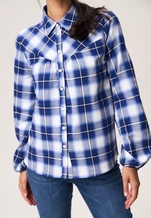 Blauw-wit geblokt overhemd van zachte stof, met een knoopsluiting aan de voorkant, puntige kraag en geraffineerde details op de schouders.