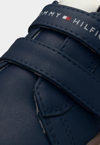 Συνθετικό παπούτσι σε ναυτικό μπλε με διπλές λουράκια βέλκρο, ραμμένες λεπτομέρειες και λογότυπο στο λουράκι. Στρογγυλερή μύτη και ομαλή υφή.