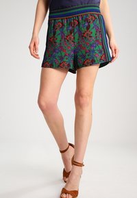 Shorts à imprimé floral en vert, rouge et bleu. Dotés d'une taille élastique avec des accents rayés. Matière en coton, longueur au-dessus du genou.