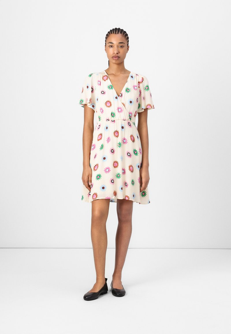 Short floral dress in cream fabric features a V-neck, short flutter sleeves, elastic waist, with multicolored flower patterns throughout.