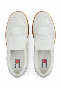 Baskets blanches avec une tige en cuir texturé, semelle en caoutchouc, fermeture à lacets et détails de logo sur la languette. Présente une semelle extérieure en gomme.