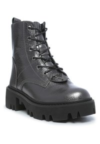 Black leather combat boot with a textured finish, lace-up design, and thick black rubber sole featuring a jagged edge.
