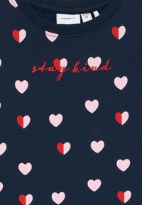 Felpa navy con motivi a cuore rosati e rossi sparsi; presenta la scritta "stay kind" ricamata in filo rosso. Materiale in cotone morbido.
