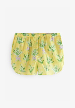 Shorts di cotone giallo con un motivo floreale in verde e viola, dotati di una vita elastica e due dettagli a bottoni nella parte anteriore.