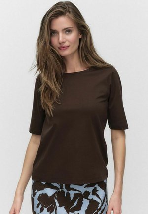Brown short-sleeve t-shirt with a round neck, made from soft fabric. Paired with a patterned blue and black skirt featuring floral designs.
