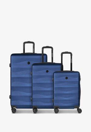 Trois valises à coque rigide bleues avec des motifs de vagues, des poignées télescopiques et quatre roulettes pivotantes, présentées en tailles grande, moyenne et petite.