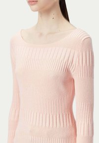 Ljusrosa långärmad tröja med ribbad yta, som har horisontella och vertikala stickade mönster. Rundad halsringning med figurnära silhuett.
