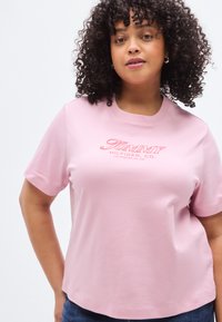 Ροζ βαμβακερό t-shirt με στρογγυλή λαιμόκοψη. Διαθέτει το λογότυπο "TOMMY HILFIGER CO." σε σκούρο ροζ στο στήθος. Με κοντά μανίκια και χαλαρή εφαρμογή.