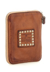 Portafoglio in pelle marrone con cerniera, caratterizzato da una toppa quadrata decorata con borchie metalliche e testo impresso. Texture liscia con finitura vintage.