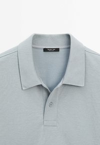 Lysegrå polo skjorte lavet af glat bomuldsblanding, med klassisk krave, tre-knaps lukning og ribbet detaljer på kraven.