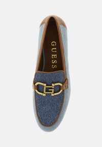 Scarpa slip-on in denim con dettagli in pelle marrone, punta arrotondata e una catena con logo dorato davanti. L'interno presenta una soletta con marchio.