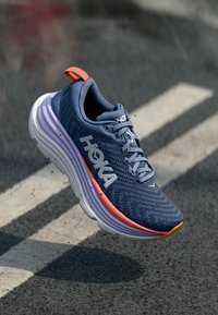 HOKA löparsko i marinblått med texturerad ovandel, rosa och lavendel accenter, vadderad sula och reflekterande logotypdetalj.