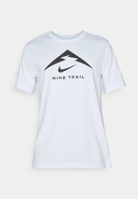 Světle modré tričko s krátkým rukávem vyrobené z bavlny, s černým trojúhelníkovým logem, ve kterém je blesk, a nápisem "NIKE TRAIL" pod ním.