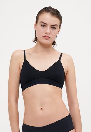 Crna bralette s V-izrezom, tankim podesivim trakama, teksturiranim donjim dijelom koji sadrži logo, glatkim materijalom i minimalističkim stilom.