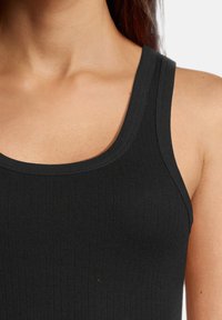 Canottiera nera con coste, spalline larghe, scollatura rotonda e design aderente che mette in mostra una consistenza liscia e elasticizzata.