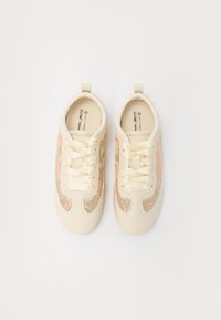 Sneaker beige con un motivo testurizzato, pannelli laterali in rete, punta arrotondata e lacci crema. Presenta un design leggero e una linguetta per un facile indossamento.