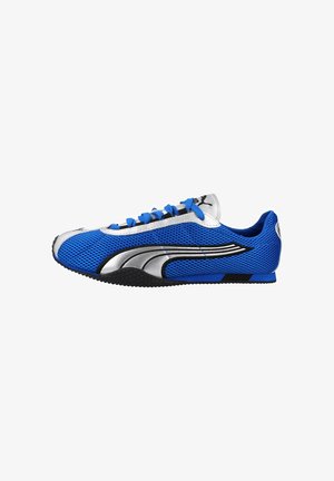 Chaussure de sport bleue et argentée à profil bas avec tige en mesh, logo noir et argent sur le côté, lacets bleus et semelle noire texturée.
