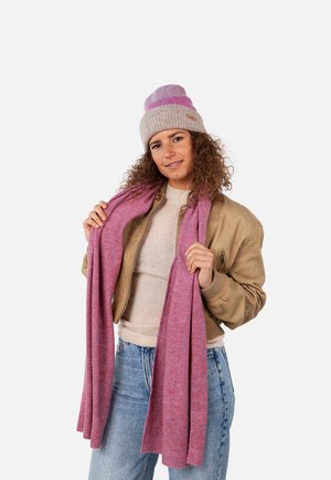 Wool beanie in light gray with purple stripe, paired with a soft pink scarf. Model wearing a tan bomber jacket and light blue jeans.