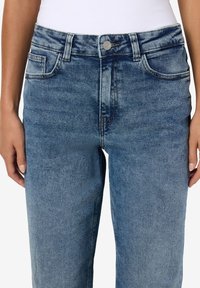 Ανοιχτού μπλε τζιν παντελόνι με κανονικό σχέδιο πέντε τσεπών, ορατές ραφές και μεταλλικό κούμπωμα στη μέση.